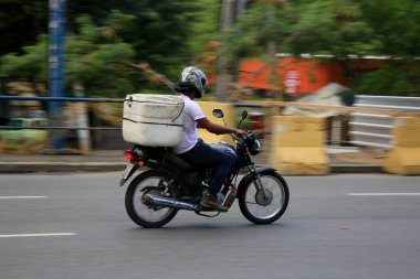 Salvador, Bahia, Brezilya - 18 Aralık 2020: Salvador şehrinde Pituba Mahallesi 'nde uygulamayla yiyecek teslimatı motorsiklet kullanılarak görülmektedir..