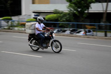 Salvador, Bahia, Brezilya - 18 Aralık 2020: Salvador şehrinde Pituba Mahallesi 'nde uygulamayla yiyecek teslimatı motorsiklet kullanılarak görülmektedir..