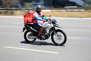 Salvador, Bahia, Brezilya - 30 Aralık 2020: Salvador şehrinde Pituba Mahallesi 'nde uygulamayla yiyecek teslimatı motorsiklet kullanılarak görülmektedir..