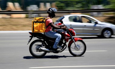 Salvador, Bahia, Brezilya - 30 Aralık 2020: Salvador şehrinde Pituba Mahallesi 'nde uygulamayla yiyecek teslimatı motorsiklet kullanılarak görülmektedir..