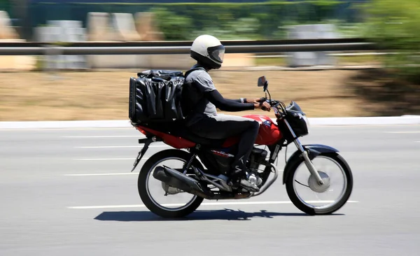 Salvador, Bahia, Brezilya - 30 Aralık 2020: Salvador şehrinde Pituba Mahallesi 'nde uygulamayla yiyecek teslimatı motorsiklet kullanılarak görülmektedir..