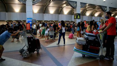 Salvador, Bahia, Brezilya - 18 Ocak 2021: Yolcu, Salvador Uluslararası Havaalanı lobisinde havayolu girişinin yanında bavul taşırken görüldü..