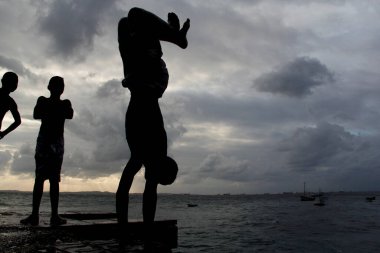 Salvador, Bahia, Brezilya - 10 Mayıs 2013: Gençler Salvador 'un Porto da Barra kentindeki Forte de Santa Maria' da dalgakırandan atlarlar.