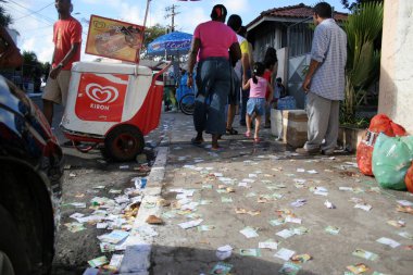 salvador, bahia, brazil - october 1, 2006: candidates' flyers are seen tossed on the street next to an electoral session in the city of Salvador. clipart