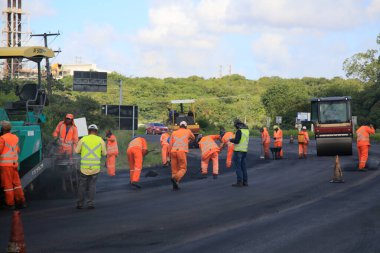 Camacari, Bahia, Brezilya - 24 Ağustos 2021: işçiler, Camacari şehrinin sanayi merkezine giriş yolunun asfalt özetini yaparken görülüyor..