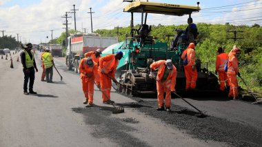 Camacari, Bahia, Brezilya - 24 Ağustos 2021: işçiler, Camacari şehrinin sanayi merkezine giriş yolunun asfalt özetini yaparken görülüyor..