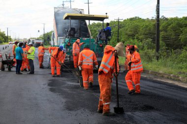 Camacari, Bahia, Brezilya - 24 Ağustos 2021: işçiler, Camacari şehrinin sanayi merkezine giriş yolunun asfalt özetini yaparken görülüyor..