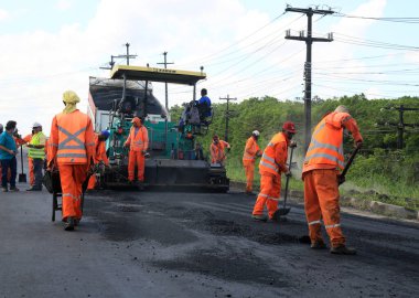Camacari, Bahia, Brezilya - 24 Ağustos 2021: işçiler, Camacari şehrinin sanayi merkezine giriş yolunun asfalt özetini yaparken görülüyor..