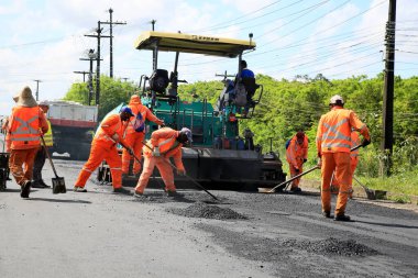 Camacari, Bahia, Brezilya - 24 Ağustos 2021: işçiler, Camacari şehrinin sanayi merkezine giriş yolunun asfalt özetini yaparken görülüyor..