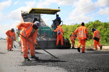 Camacari, Bahia, Brezilya - 24 Ağustos 2021: işçiler, Camacari şehrinin sanayi merkezine giriş yolunun asfalt özetini yaparken görülüyor..
