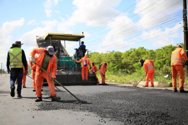 Camacari, Bahia, Brezilya - 24 Ağustos 2021: işçiler, Camacari şehrinin sanayi merkezine giriş yolunun asfalt özetini yaparken görülüyor..