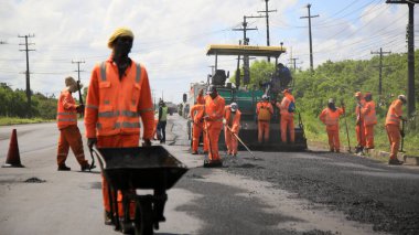 Camacari, Bahia, Brezilya - 24 Ağustos 2021: işçiler, Camacari şehrinin sanayi merkezine giriş yolunun asfalt özetini yaparken görülüyor..