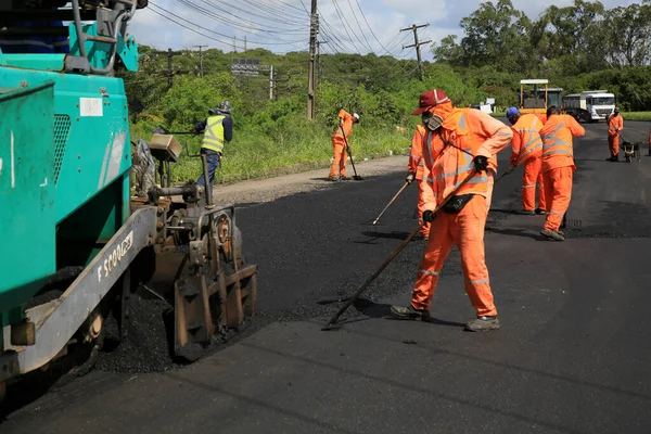 Camacari, Bahia, Brezilya - 24 Ağustos 2021: işçiler, Camacari şehrinin sanayi merkezine giriş yolunun asfalt özetini yaparken görülüyor..