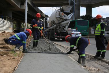 Salvador, Bahia, Brezilya - 7 Ağustos 2025: Salvador kentindeki yaya kaldırımına beton döken inşaat işçileri görülüyor
