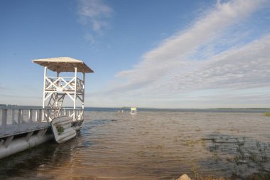 Gölde beyaz ahşap boş iskele. Sabah gökyüzünün ve gölün manzarası.