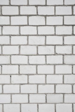 Çatlakları ve çimento eklemleri olan büyük, beyaz tuğlalardan oluşan dikey bir duvar. 