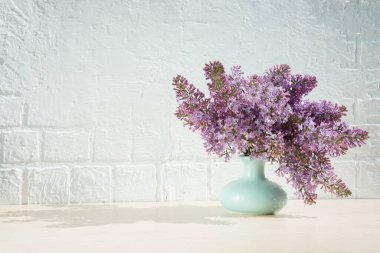 Vazodaki mor leylak demeti beyaz tuğladan bir duvarın arka planında 