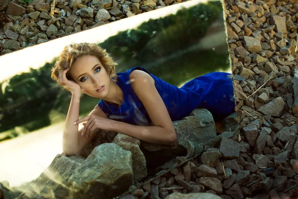 The girl lying on stones is reflected in a mirror — Stock Photo, Image