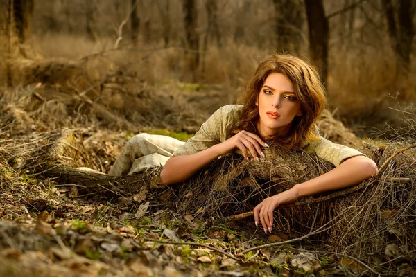Belle fille se trouve sur une bûche dans le bois de printemps — Photo