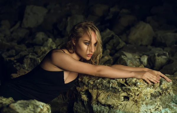 Schönes Mädchen mit langen Haaren sitzt nachts auf Steinen — Stockfoto