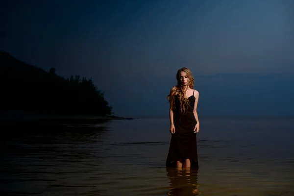 girl with long hair in black dress costs in water