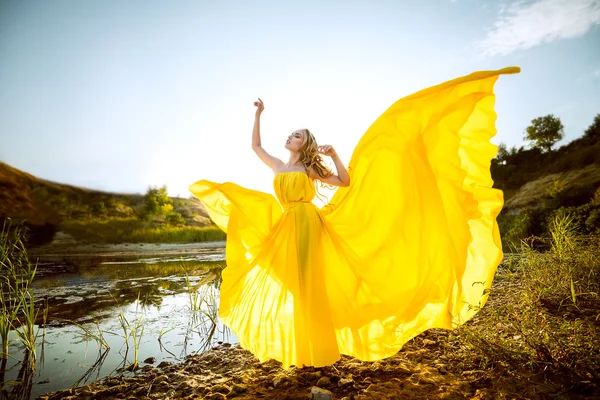 La belle fille aux cheveux longs dans la robe jaune flottante — Photo