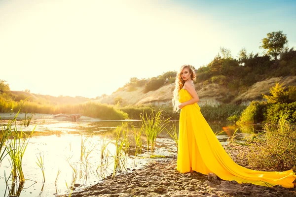 Belle fille aux cheveux longs en robe jaune coûte à terre Photo De Stock