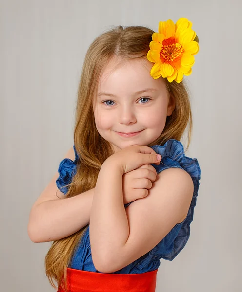 A bela menina com uma flor amarela no cabelo sorri Imagens Royalty-Free