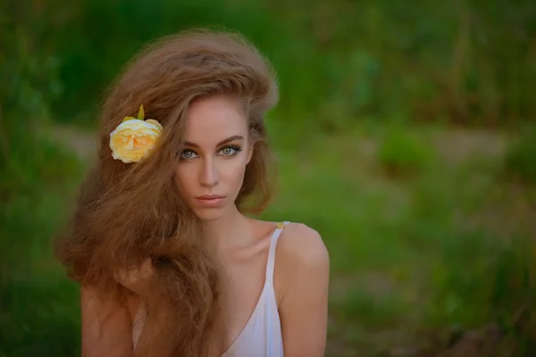 Schönes Mädchen mit einer Blume im langen blonden Haar — Stockfoto