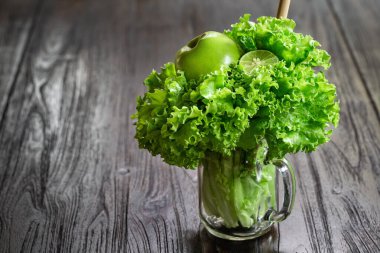 Salata yaprakları, yeşil elma ve kireç, ahşap masada duran kavanoz bardakta, kopyalama alanı ile sağlıklı meyve püresi pişirmeye hazır. Yeşil vejetaryen çiğ yemek..