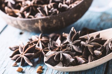 Tam yıldız anason sepetinde ve kaşıkta tohumlar mavi rustik ahşap arka planda, Hint baharatı, doğal alternatif tıp, güzel kokulu yiyecek, yakın çekim tonlu görüntü 