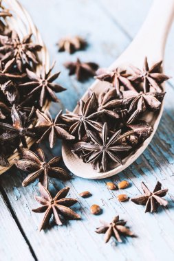 Tam yıldız anason sepetinde ve kaşıkta tohumlar mavi rustik ahşap arka planda, Hint baharatı, doğal alternatif tıp, güzel kokulu yiyecek, yakın çekim tonlu görüntü 