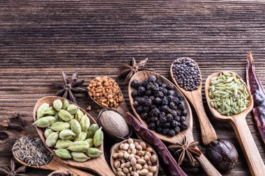 Ahşap arka planda farklı Hint baharatları var. Karabiber, çemen otu, anason, tarçın, kakule, hindistan cevizi, karanfil, kimyon. Sağlıklı yemek..