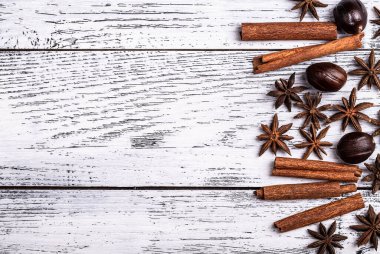 Tarçın anason yıldızları hindistan cevizi sosunu beyaz ahşap arka planın sağ tarafına sürer. Üst görünüm.