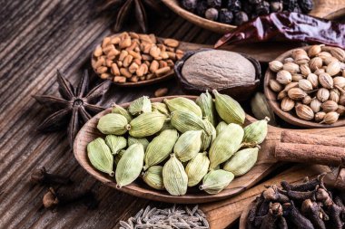 Ahşap arka planda farklı Hint baharatları var. Karabiber, çemen otu, anason, tarçın, kakule, hindistan cevizi, karanfil, kimyon. Sağlıklı yemek..