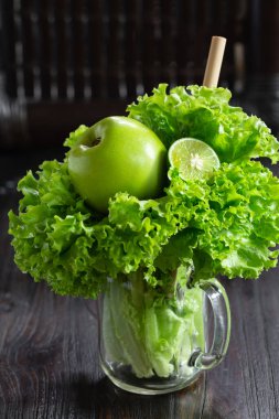 Salata yaprakları, yeşil elma ve kireç, ahşap masada duran kavanoz bardakta, kopyalama alanı ile sağlıklı meyve püresi pişirmeye hazır. Yeşil vejetaryen çiğ yemek..