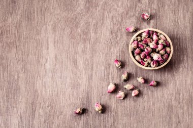 Ahşap kasede pembe kırmızı kurumuş gül tomurcukları ve eski ahşap arka plan fotokopi odası manzarası. Sağlıklı egzotik Asya organik çayı.