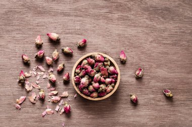 Ahşap kasede pembe kırmızı kurumuş gül tomurcukları ve eski ahşap arka plan fotokopi odası manzarası. Sağlıklı egzotik Asya organik çayı.