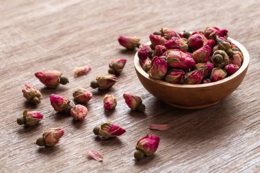 Ahşap kasede pembe kırmızı kurumuş gül tomurcukları ve eski ahşap arka plan kopyasının yaprakları. Sağlıklı egzotik Asya organik çayı.