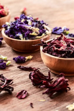 Köy arka planında, ahşap kaselerde çay çeşitleri. Çeşitli bitkisel sağlıklı çay türleri gül, amber çiçeği, kelebek bezelyesi, kasımpatı..