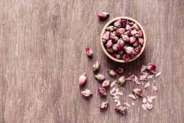 Ahşap kasede pembe kırmızı kurumuş gül tomurcukları ve eski ahşap arka plan fotokopi odası manzarası. Sağlıklı egzotik Asya organik çayı.