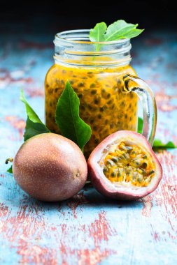 Cam bir kavanozda tutku meyvesi ve mavi ahşap masa üzerinde yarım meyve dikey. Sağlıklı beslenme, çiğ yemek, doğal vitamin, hasat, vejetaryen, vejetaryen.