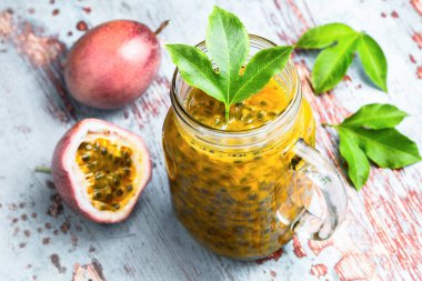 Cam kavanozda tutku meyvesi. Gri ahşap masa üzerinde yarım meyve. Sağlıklı beslenme, çiğ yemek, doğal vitamin, hasat, vejetaryen, vejetaryen.