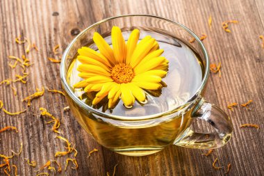 Ahşap arka planda kurumuş çiçeklerle şeffaf cam bardakta bitkisel çay. Sağlıklı çiçek çayı, alternatif tıp.