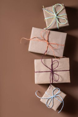 Kahverengi zemin üzerinde çok renkli kurdeleler bulunan kraft kağıdına sarılı Noel hediyesi kutuları dikey yatıyordu. 