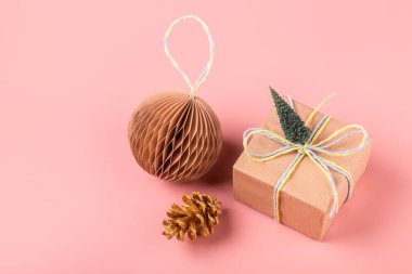 Yeni Yıl ve Noel 'in yaratıcı kompozisyonu, pastel pembe arka plan üzerine bir hediye ve dekorasyonla yapıldı..