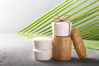 El yapımı doğal hindistan cevizi yağı. Beyaz sabun. Palmiye yaprağı ve gri beton arka plan. Vücut bakımı, sıfır atık.