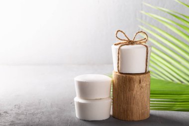 El yapımı doğal hindistan cevizi yağı. Beyaz sabun. Palmiye yaprağı ve gri beton arka plan. Vücut bakımı, sıfır atık.