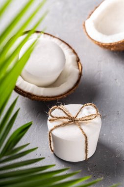 El yapımı doğal hindistan cevizi yağı. Beyaz sabun. Palmiye yaprağı ve gri beton arka plan. Vücut bakımı, sıfır atık.