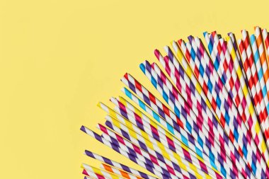 Çok renkli kamış kağıt tüpleri. Kopyalama alanı olan parlak sarı pastel arka planda parti için plastik yok. Üst manzara, düz uzanma.